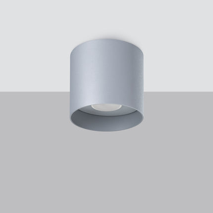 Plafonnier cylindrique gris vu en saillie sur un plafond, ambiance intérieure sobre
