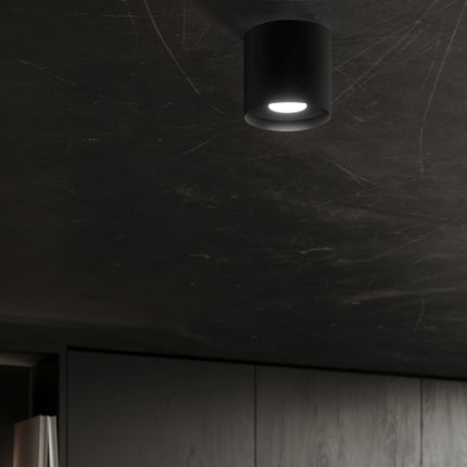 Plafonnier noir allumé au plafond d'une pièce sombre, effet lumineux discret