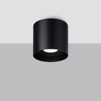 Plafonnier cylindrique noir vu en saillie sur un plafond, ambiance contrastée