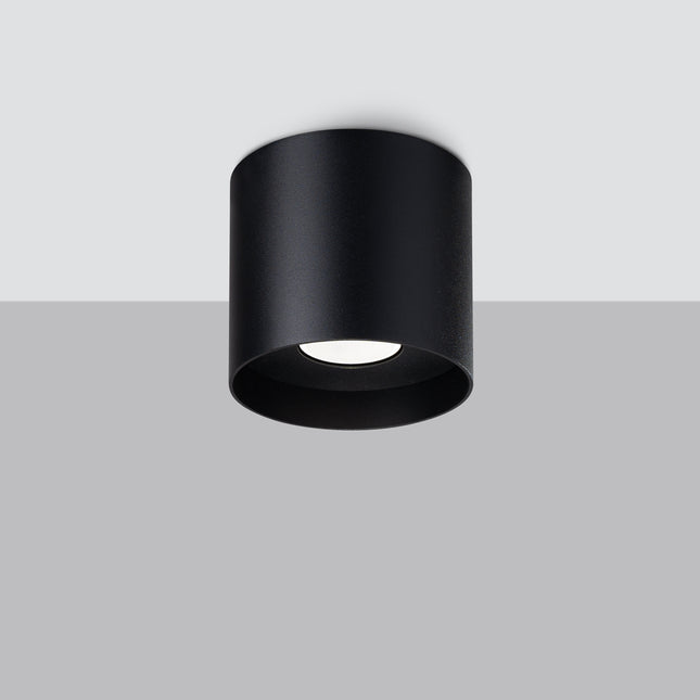 Plafonnier cylindrique noir vu en saillie sur un plafond, ambiance contrastée