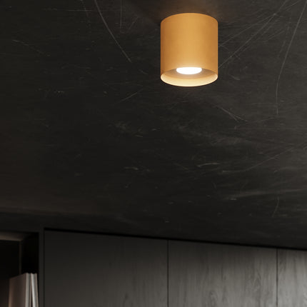 Plafonnier doré allumé au plafond d'une pièce sombre, effet lumineux discret