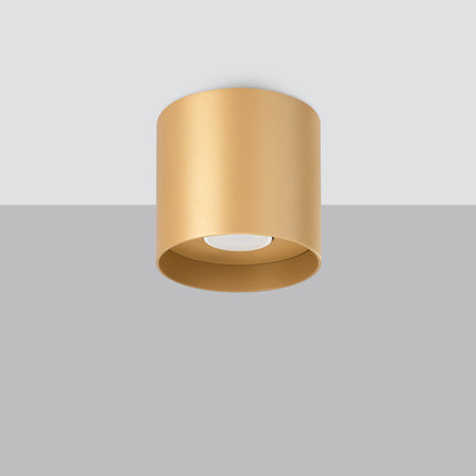 Plafonnier cylindrique doré vu en saillie sur un plafond, ambiance intérieure chaleureuse