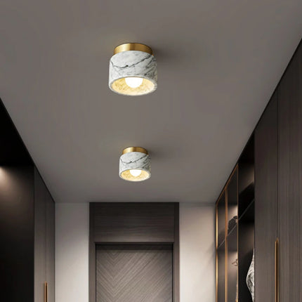 Deux plafonniers cylindre en marbre blanc au plafond d'un couloir contemporain
