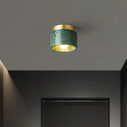 Plafonnier cylindre en marbre vert au plafond d'un couloir sombre et graphique