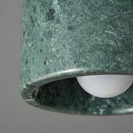 Gros plan sur la texture du marbre vert moucheté du plafonnier cylindre