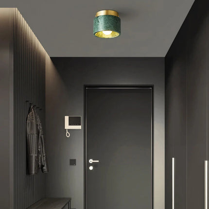 Plafonnier cylindre en marbre vert au-dessus d'une porte dans une entrée sombre