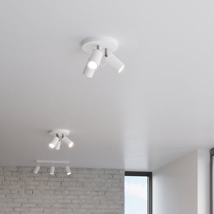 Deux plafonniers 3 spots blancs allumés dans un couloir lumineux avec mur en brique