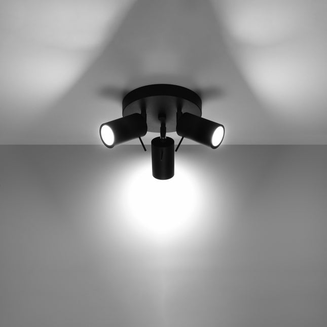 Plafonnier 3 spots noir allumé au plafond, faisceau lumineux dirigé vers le sol
