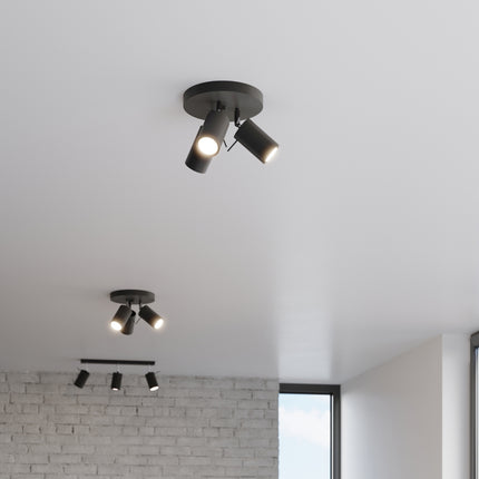 Deux plafonniers 3 spots noirs allumés dans un couloir lumineux avec mur en brique