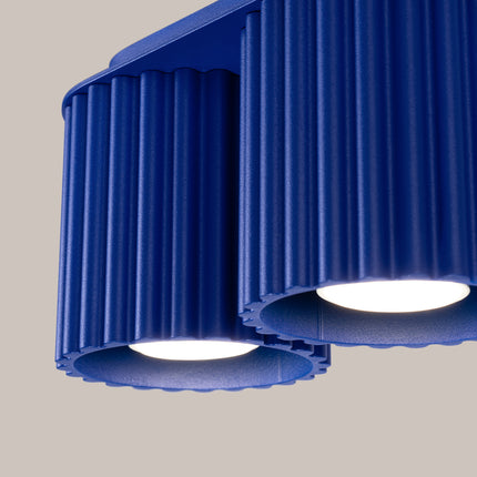 Détail des deux cylindres cannelés en aluminium bleu outremer du plafonnier Aura allumé