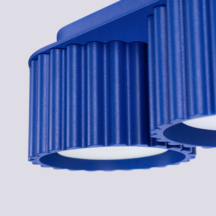 Gros plan sur les rainures verticales de l'aluminium bleu outremer du plafonnier Aura