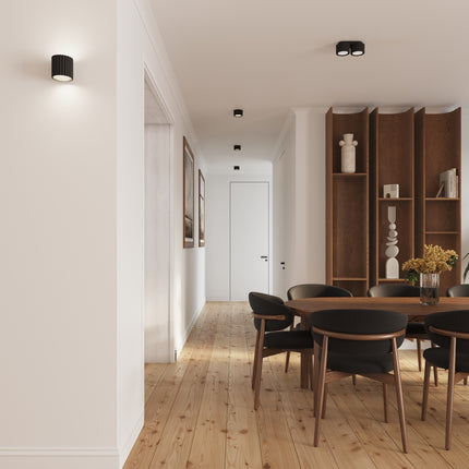 Plafonnier double Aura noir éclairant un couloir prolongé d'une salle à manger contemporaine
