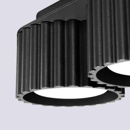 Gros plan sur les rainures verticales en aluminium noir mat du plafonnier double Aura