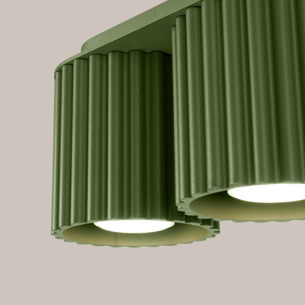 Gros plan sur la surface cannelée en aluminium vert olive du plafonnier double Aura