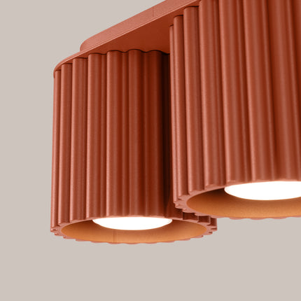 Détail des cannelures et de la finition mate rouge ocre du plafonnier double spot Aura