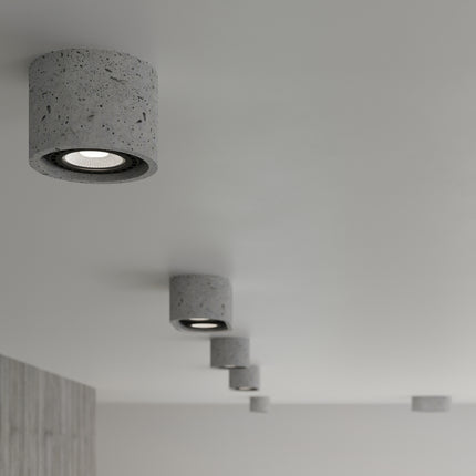 Détail du plafonnier double spot en béton brut, texture minérale, spots orientés