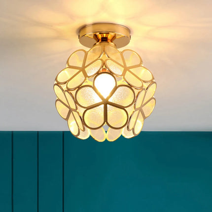 Plafonnier fleur en verre à pétales jaune crème allumé dans un couloir au mur bleu canard