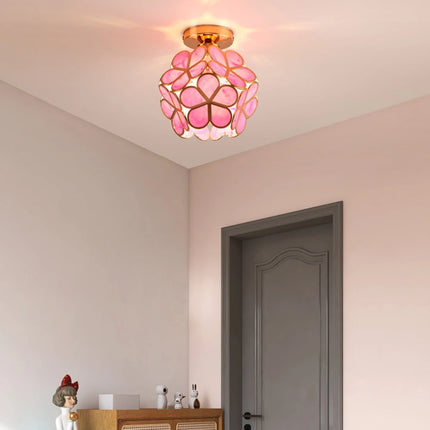 Plafonnier fleur en verre à pétales rose installé dans une entrée aux murs pastel