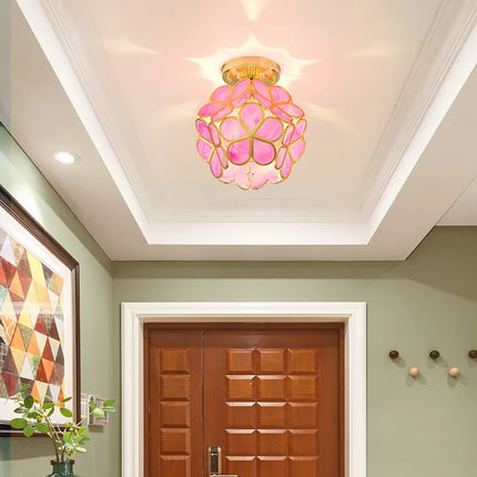 Plafonnier fleur en verre à pétales rose dans un hall à double porte en bois