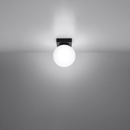 Plafonnier Globe Solis noir allumé au plafond, lumière douce diffusée par le globe opale