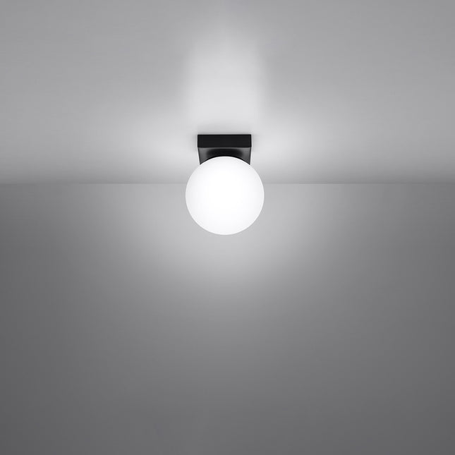 Plafonnier Globe Solis noir allumé au plafond, lumière douce diffusée par le globe opale