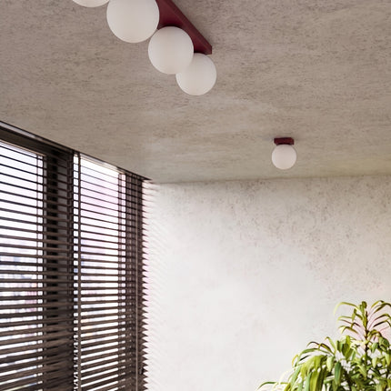 Plafonnier Globe Solis 2 globes bordeaux dans une pièce claire à stores en bois