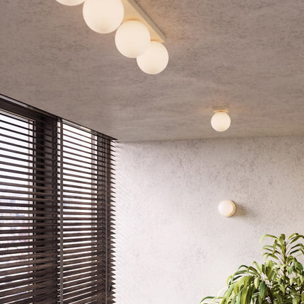 Plafonnier Globe Solis 3 globes beige dans une pièce claire à stores en bois