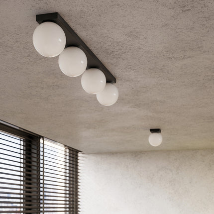 Détail de plafonniers Globe Solis noirs au plafond, globes opale blancs alignés
