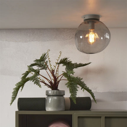 Plafonnier Helsinki galet en verre gris clair, ambiance salon avec plante
