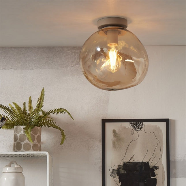 Plafonnier Helsinki en verre soufflé ambré forme galet, ambiance salon avec plante