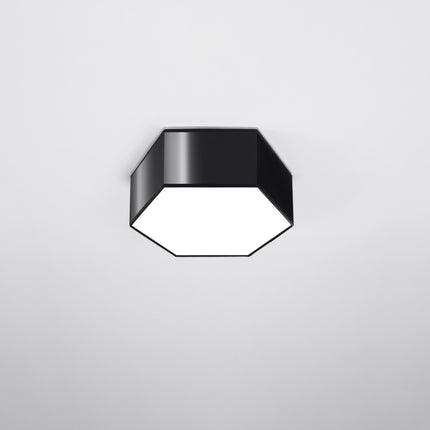 Plafonnier Hexagonal Pure 11 noir allumé sur fond gris foncé, lumière chaude diffusée par le hublot blanc.