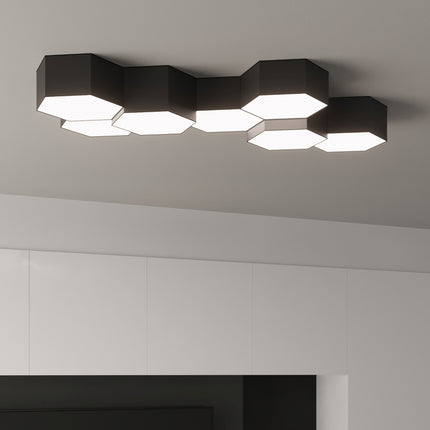 Plafonniers Hexagonal Pure noirs allumés, gros plan de la composition au-dessus d'un meuble bas.