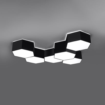 Plafonniers Hexagonal Pure noirs assemblés au-dessus d'un meuble TV, composition allumée diffusant une lumière chaude.
