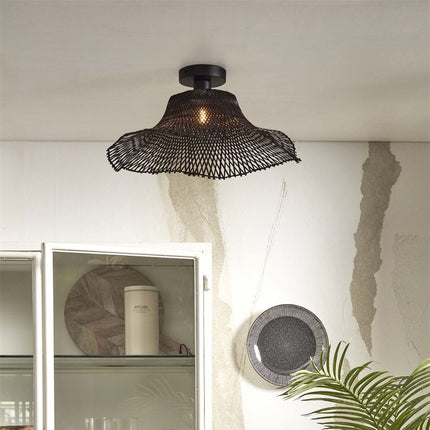 Ibiza Wavy ceiling light in braided black bamboo on the ceiling of a living room, wavy lampshade diffusing a warm light