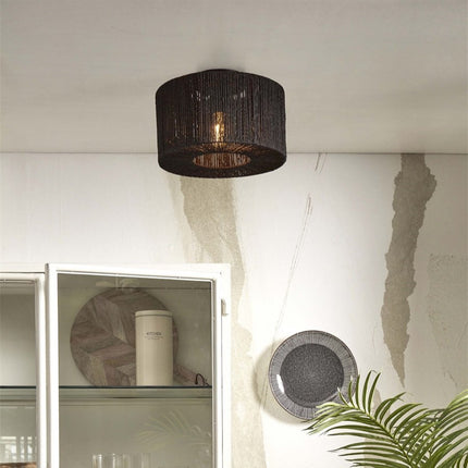 Round ceiling light in braided black jute on the ceiling above a white display cabinet, warm light lit