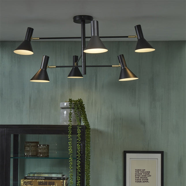 Izmir ceiling light black and gold installed in a living room with green walls, near a display cabinet in wood