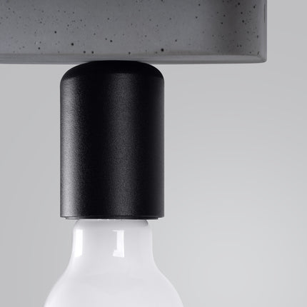 Gros plan sur la douille cylindrique en métal noir mat du plafonnier Modulo Industriel en béton