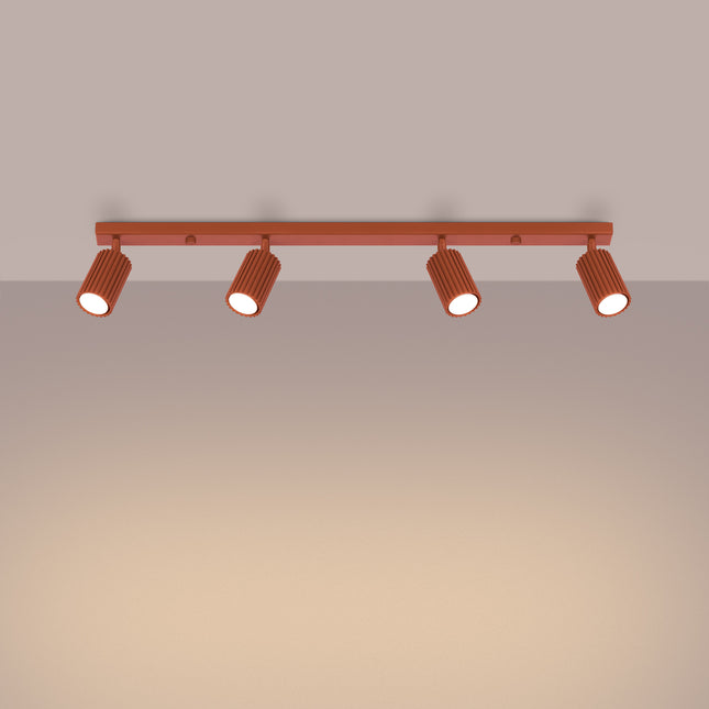 Vue en angle du plafonnier Oslo 4 lumières rouge ocre, spots cannelés en aluminium dans une ambiance chaleureuse.
