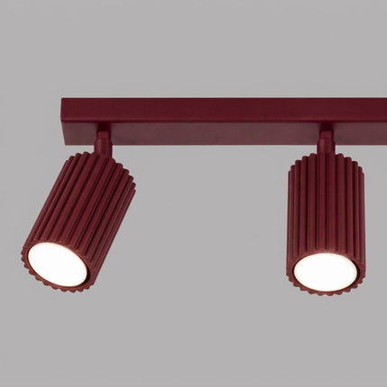 Plafonnier Oslo barre 3 spots orientables 45 cm bordeaux sur fond coloré, vue de trois quarts