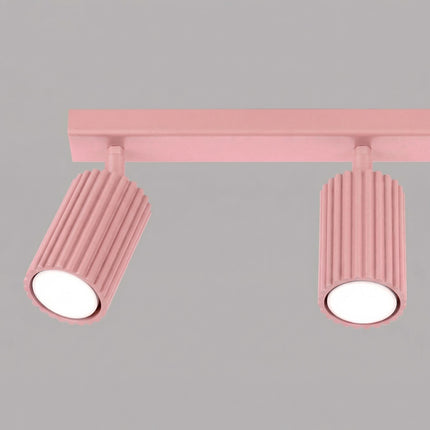 Plafonnier Oslo barre 3 spots orientables 45 cm rose poudré sur fond coloré, vue de trois quarts