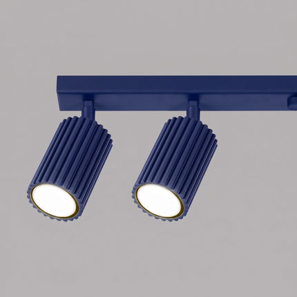 Plafonnier Oslo barre 6 spots orientables 117 cm bleu outremer sur fond coloré, vue de trois quarts