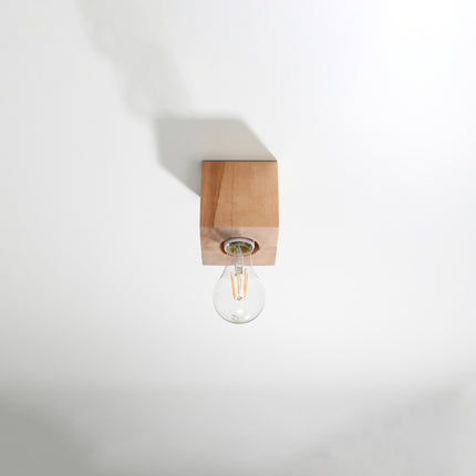 Plafonnier cube en bois naturel fixé au plafond, ampoule filament E27 apparente éteinte, fond clair.