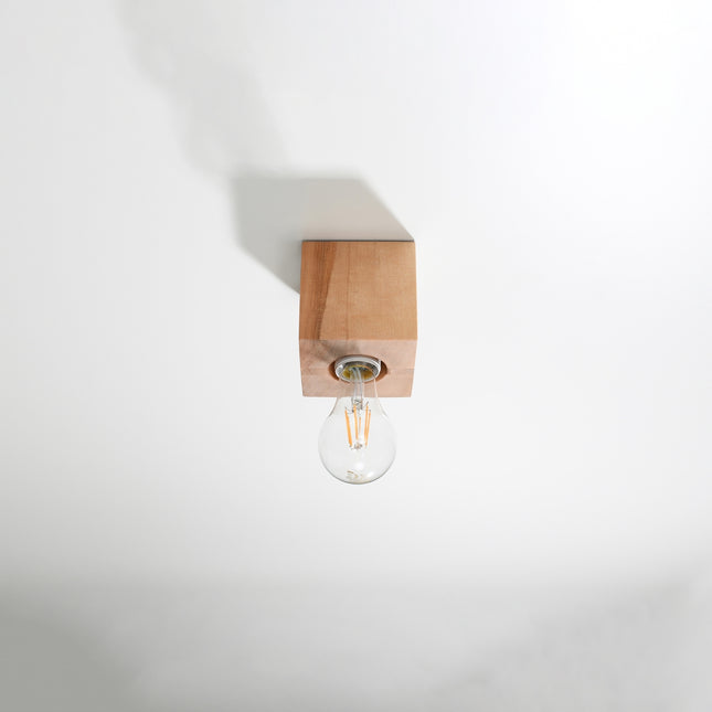 Plafonnier cube en bois naturel fixé au plafond, ampoule filament E27 apparente éteinte, fond clair.