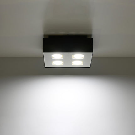 Plafonnier Quadruple Raffiné noir projetant un faisceau de lumière vers le bas