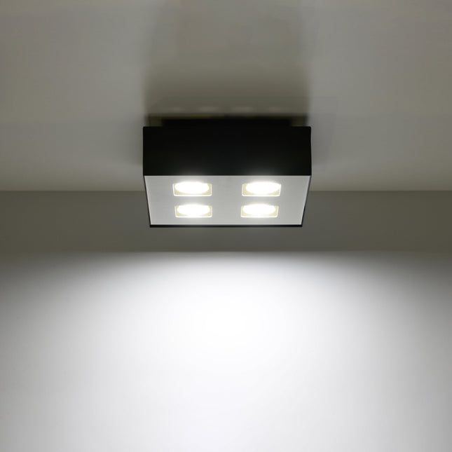 Plafonnier Quadruple Raffiné noir projetant un faisceau de lumière vers le bas
