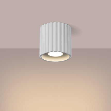 Aura ceiling light lit on the ceiling, warm light diffused under the fluted white spotlight