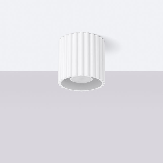 Spot plafonnier Aura blanc cannelé fixé au plafond dans une pièce claire
