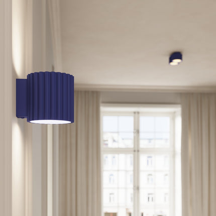 Plafonnier spot Aura bleu outremer au plafond d'une pièce lumineuse, applique assortie au premier plan