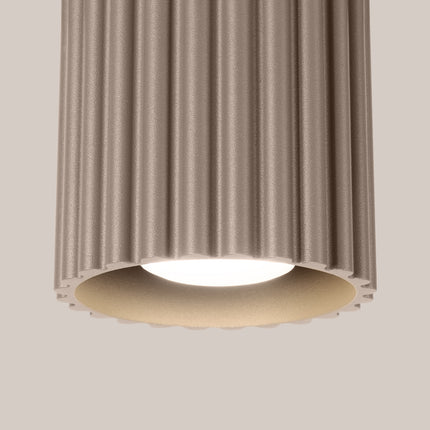 Détail du corps rainuré du plafonnier spot Aura taupe et de sa source lumineuse allumée