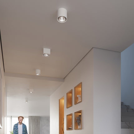 Plafonniers spots cylindriques blancs alignés au plafond d'un couloir aux niches en bois clair